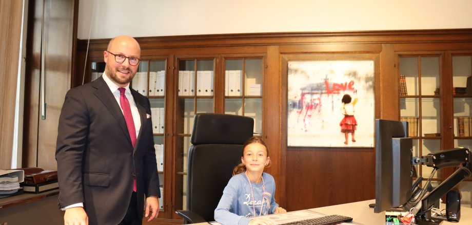 Bürgermeister Michael Gerdhenrich stehend mit Juli Pröpper an seinem Schreibtisch