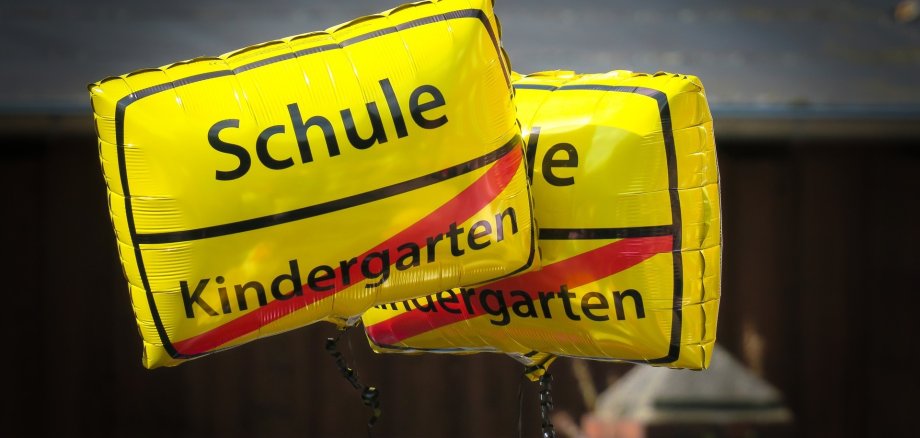 Luftballon mit nachempfundenem Stadteingangsschild Kindergarten durchgestrichen Schule nicht