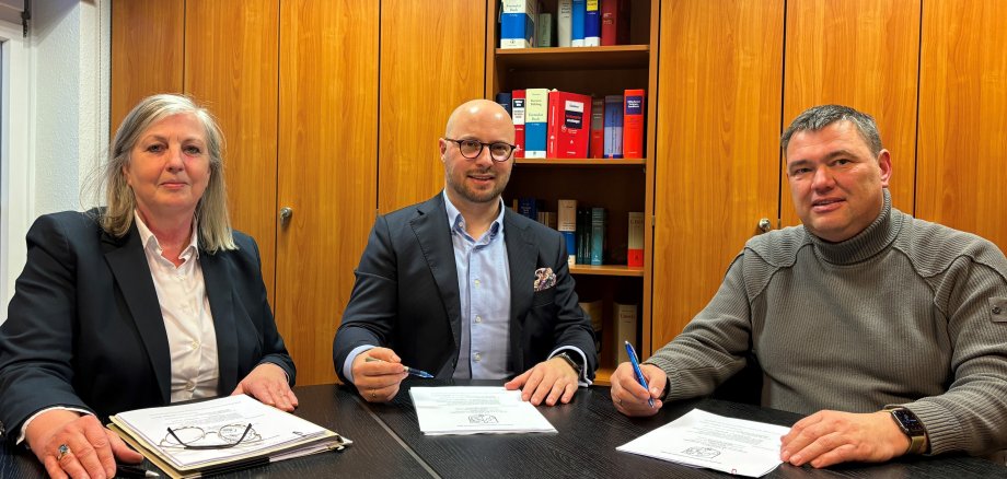 Bürgermeister Michael Gerdhenrich (Mitte) und Marc Arning haben im Beisein von Ruth Möller (amtlich bestellte Vertreterin des Notars) den Kaufvertrag unterzeichnet.